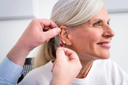 Ältere Frau erhält ein Hörgerät im Ohr für bessere Hörakustik und Hörhilfe.